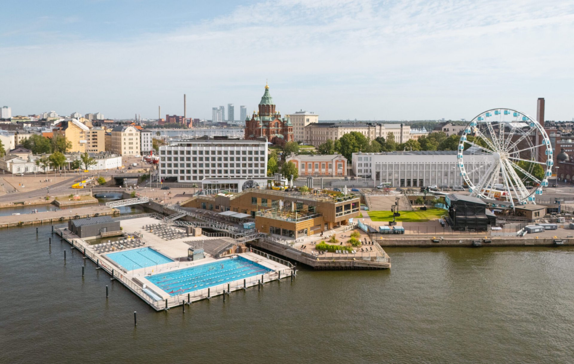 Allas Sea Pool — aerial view of the pool complex on Helsinki's South Harbour with Helsinki Cathedral and SkyWheel beyond
