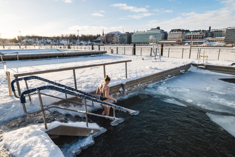 Allas Sea Pool — cold water swimmer entering the Baltic in winter, snow on the deck