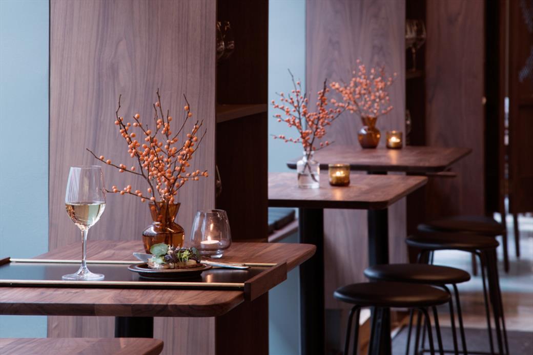 Arakataka — walnut tables with white wine and seasonal floral arrangements