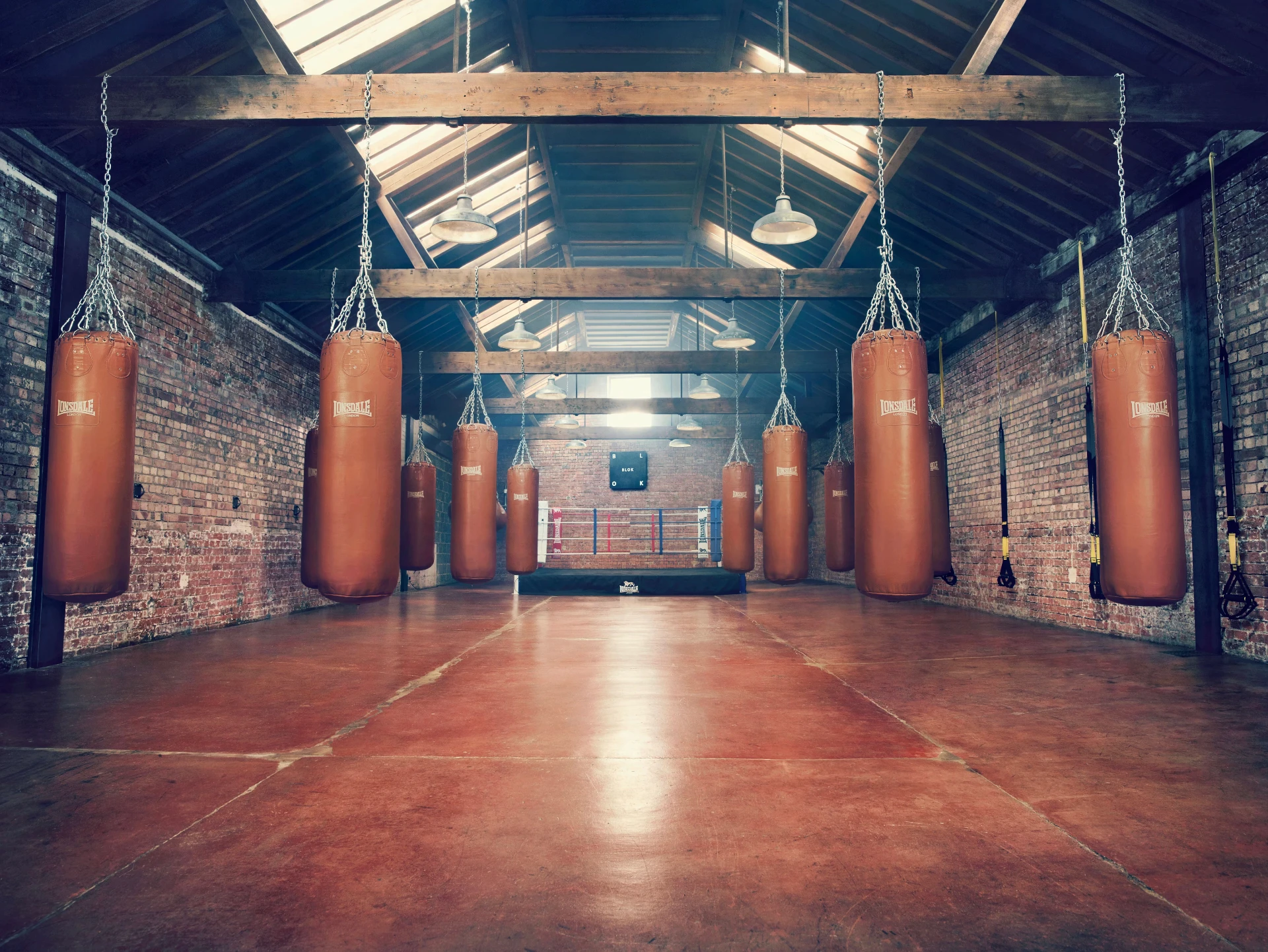 BLOK Clapton boxing hall — Lonsdale bags hanging from the vaulted tram depot roof beams above a ring