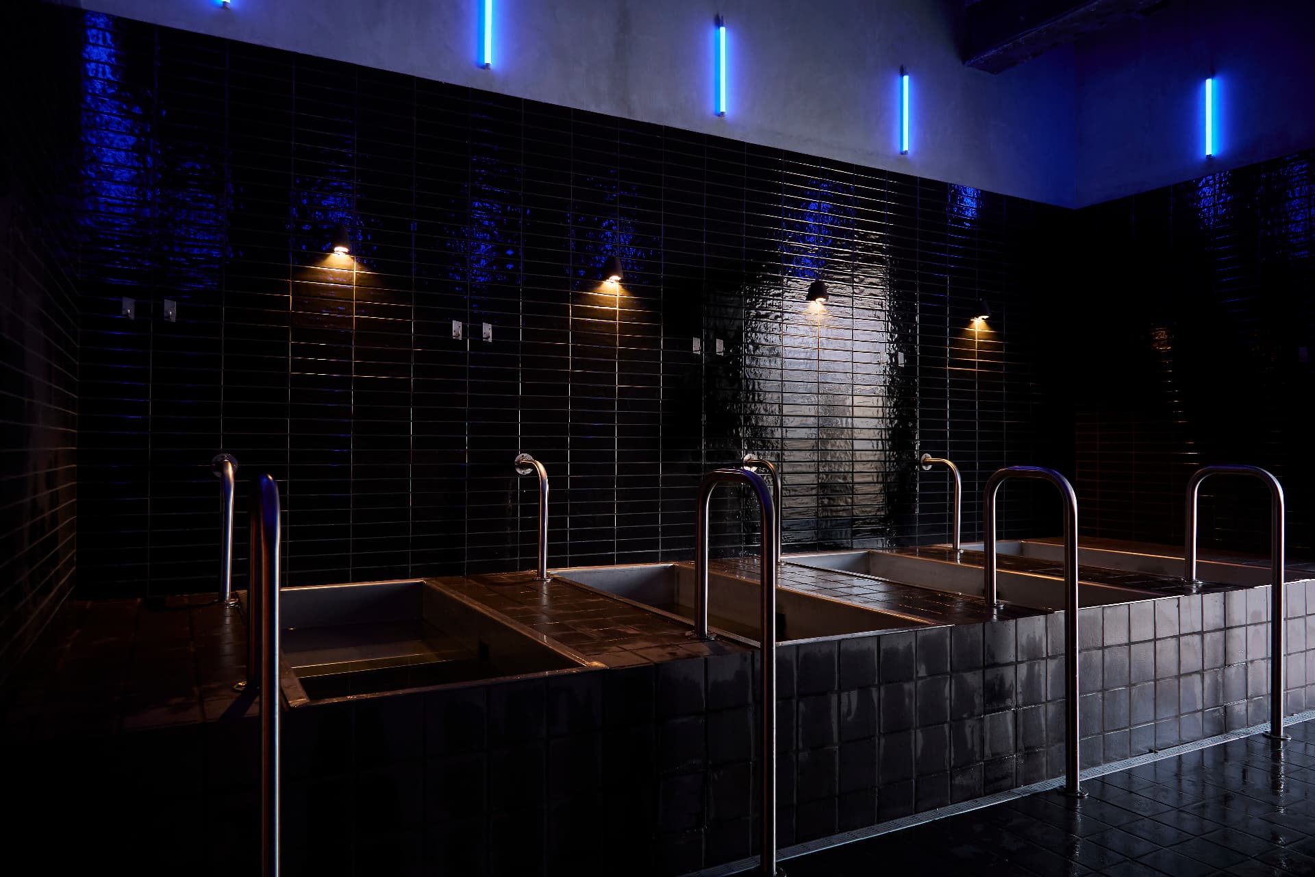 BLOK Clapton contrast therapy — dark tiled plunge pools lit by blue neon