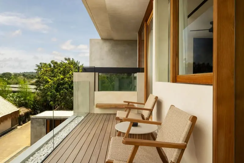 Private balcony with woven lounge chairs, timber decking and glass balustrade at Body Factory Lifestyle Residence Uluwatu