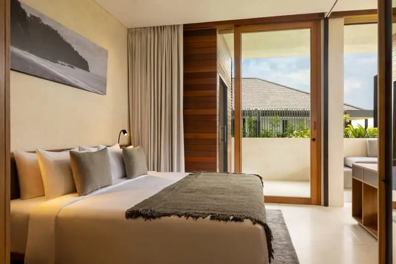 Bedroom at Body Factory Lifestyle Residence Uluwatu with linen bedding, framed coastal photograph and sliding doors to a private terrace