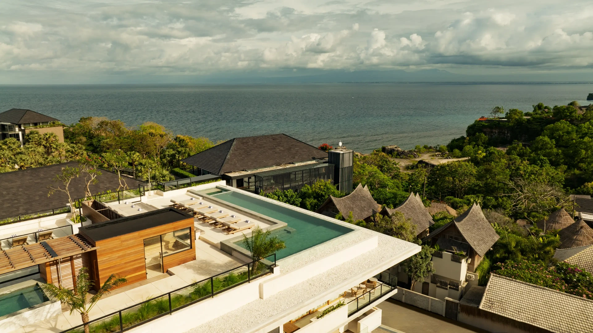 Rooftop infinity pool and sunbeds at Body Factory Lifestyle Residence Uluwatu, with views across the Bukit Peninsula to the Indian Ocean