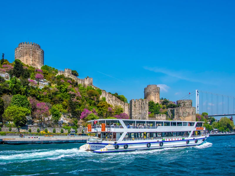 A public ferry passing Rumeli Hisarı on the Bosphorus, the fortress walls above the shoreline