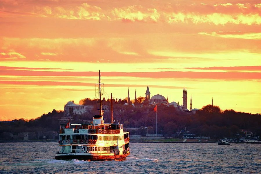 A Şehir Hatları ferry on the Bosphorus at sunset, the domes and minarets of the old city behind it