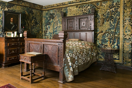 Chavenage House — Cromwell Room with carved oak bed and tapestry-hung walls