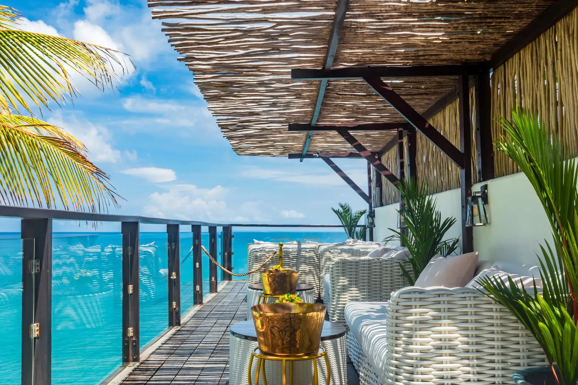 El Kabron sunset deck — bamboo-roofed terrace with wicker sofas overlooking the Indian Ocean from the Uluwatu cliff edge