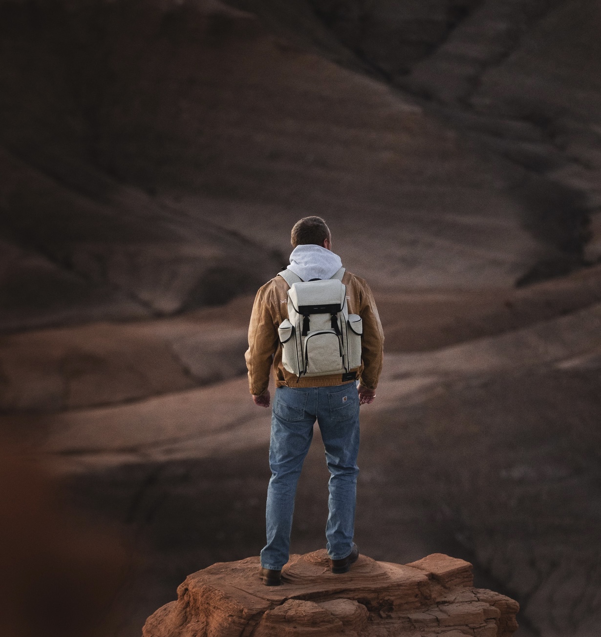 Man standing at the edge of a canyon wearing a Grams28 backpack
