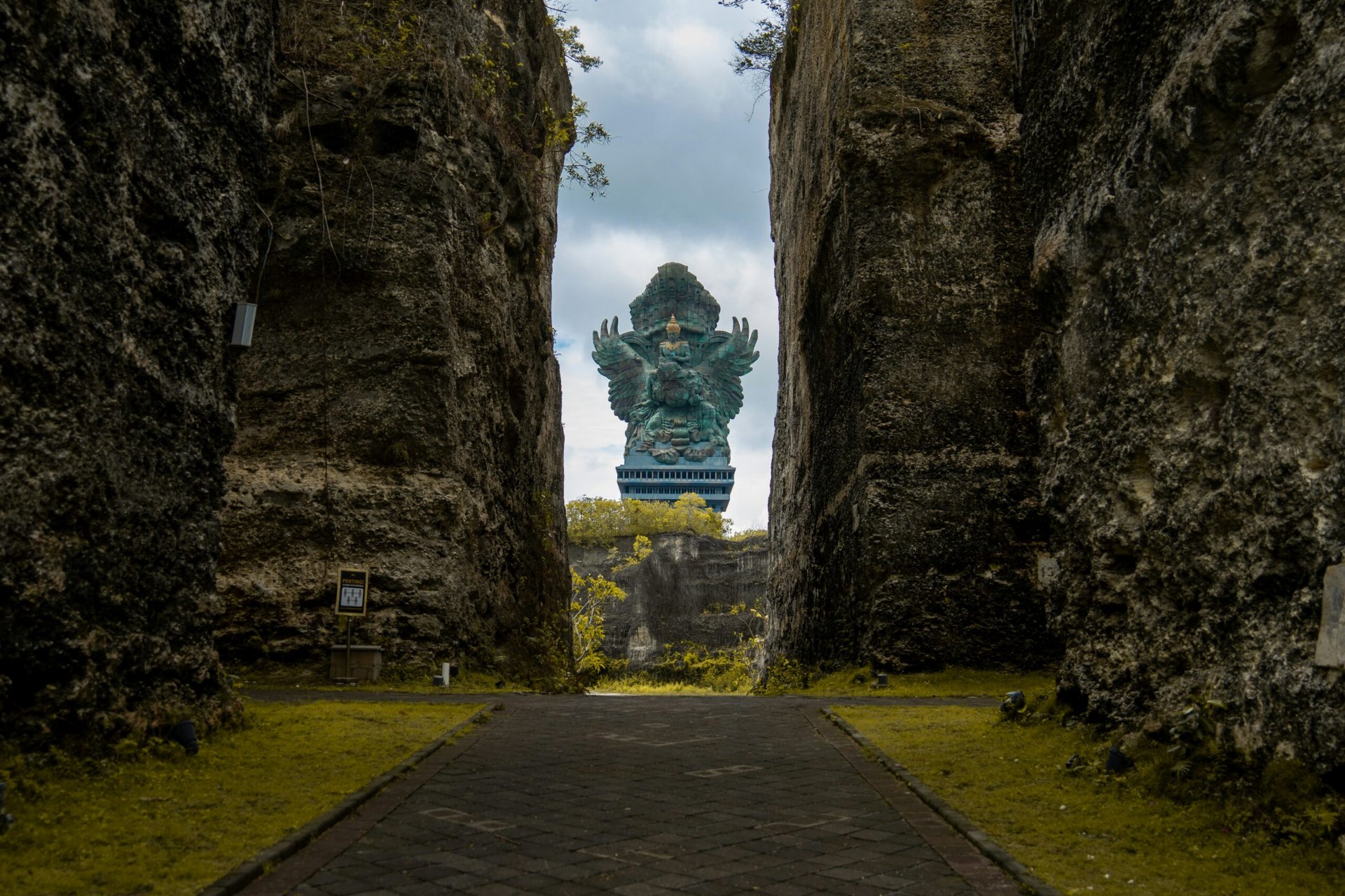 Garuda Wisnu Kencana statue framed by the limestone rock cut at the cultural park's entrance plaza