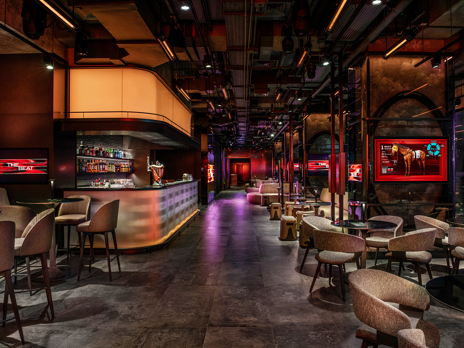 The Beat trackside bar and lounge at Happy Valley — a dim industrial interior with a long illuminated counter, scattered low tables, screens showing horses, and warm red lighting