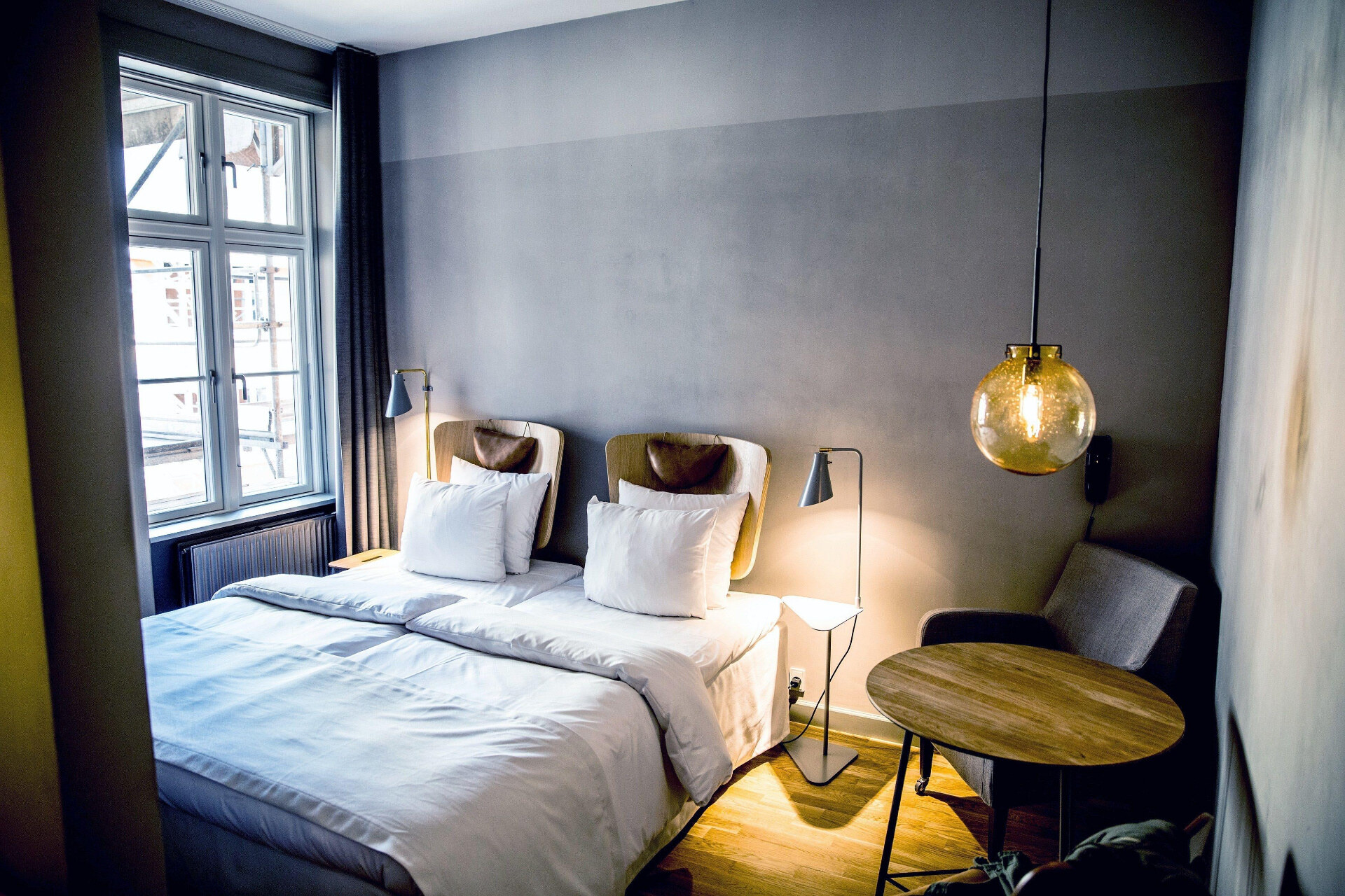 Hotel SP34 — guest suite with concrete walls, leather chair and pendant lighting