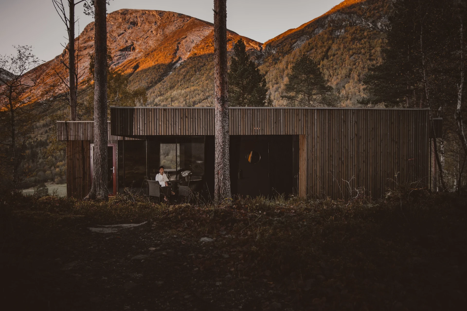 Juvet Landscape Hotel — timber pavilion at dusk with mountains beyond