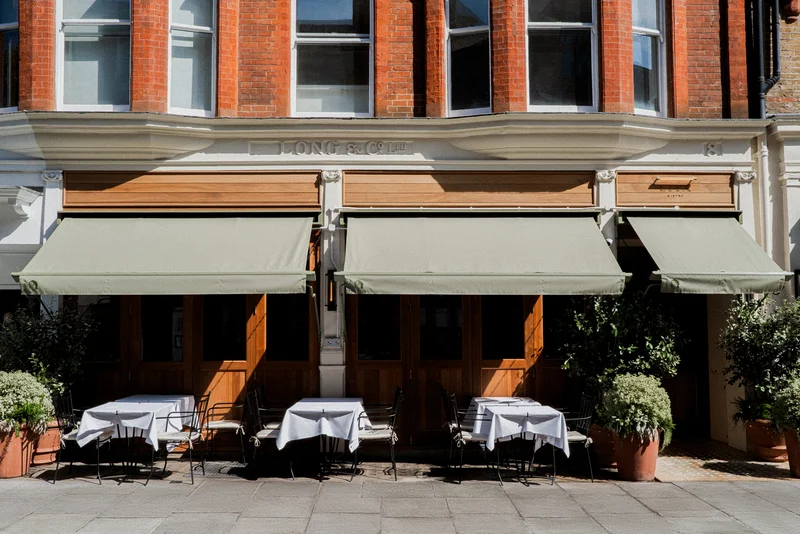 Lita, Marylebone — the restaurant's Paddington Street frontage with sage-green awnings, wooden shutters, olive and bay trees and pavement tables set with white linen