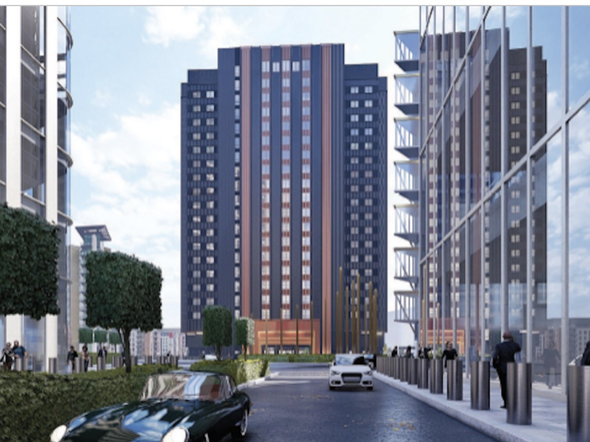 Locke London Canary Wharf — exterior view of the new 19-storey aparthotel tower in Wood Wharf, with its dark cladding and bronze vertical fins set against the surrounding glass buildings of Canary Wharf