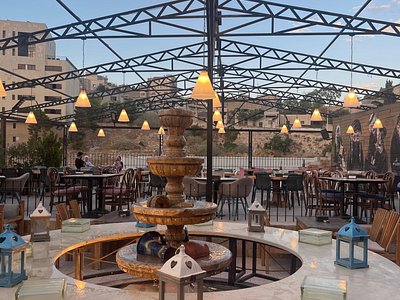 Mijana — rooftop terrace at dusk with central stone fountain, lantern-style lighting and views over Amman