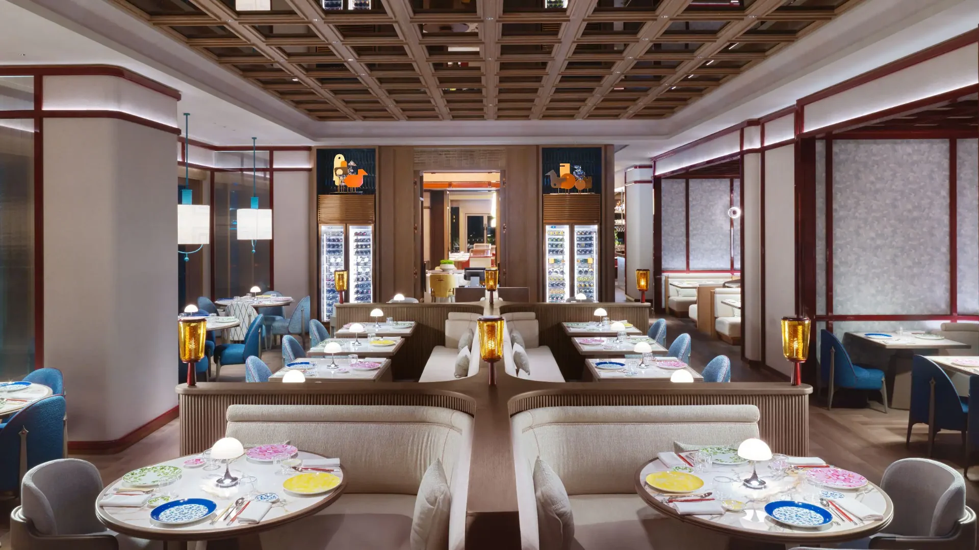The main dining room at One Duck Lane with coffered timber ceiling, red lacquered detailing, blue upholstered chairs and amber table lamps