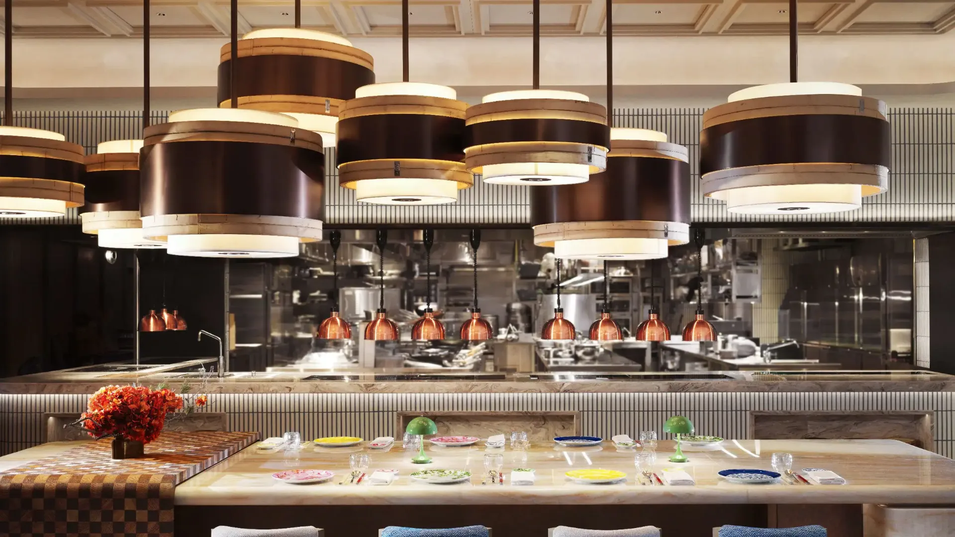 The chef's table at One Duck Lane with oversized bamboo steamer light fixtures hanging above and copper heat lamps over the open kitchen pass behind