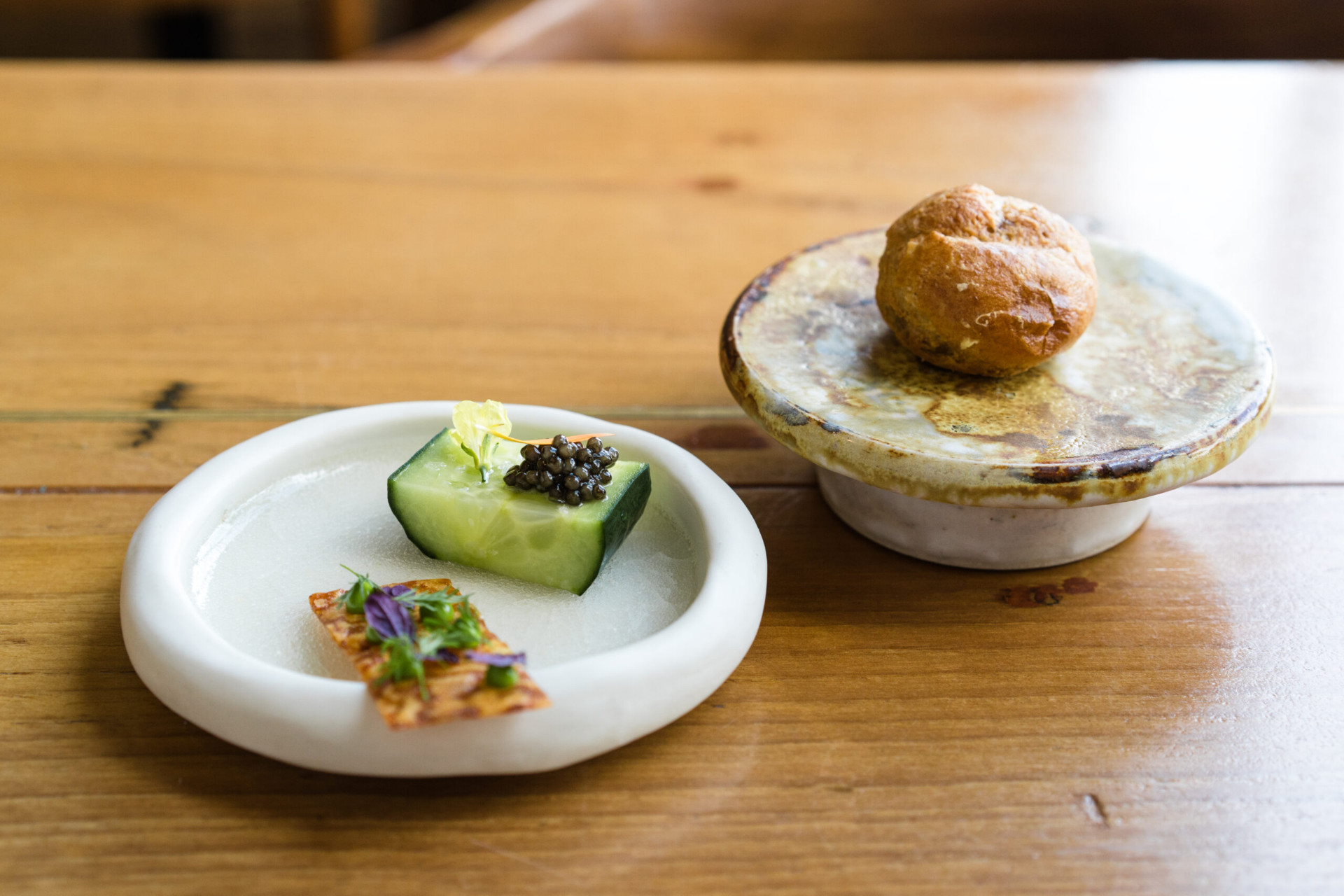 An opening course at Ox Belfast — cucumber topped with caviar alongside a freshly baked bread bun on a ceramic stand