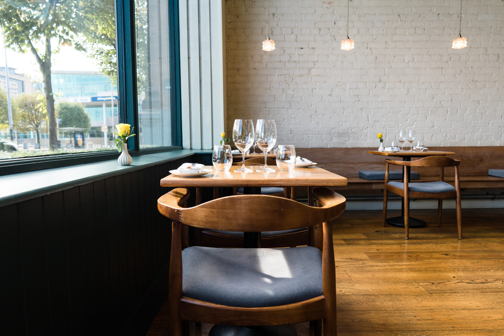 An upstairs window table at Ox Belfast — a wooden table set with stemware, looking out onto the River Lagan