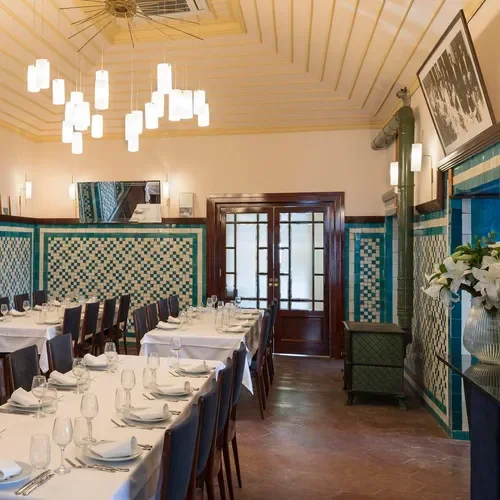 A long table laid for lunch at Pandeli, white linen and green-and-white tiled walls beneath pendant lights