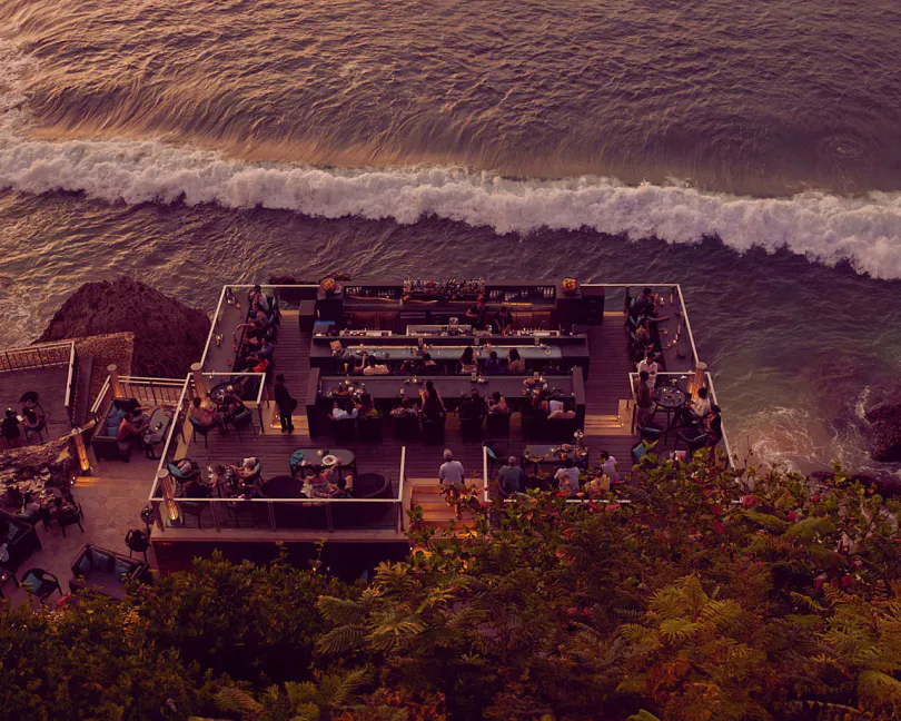 Overhead view of Rock Bar at sunset — the bar platforms glow in warm light with waves rolling across the Indian Ocean below