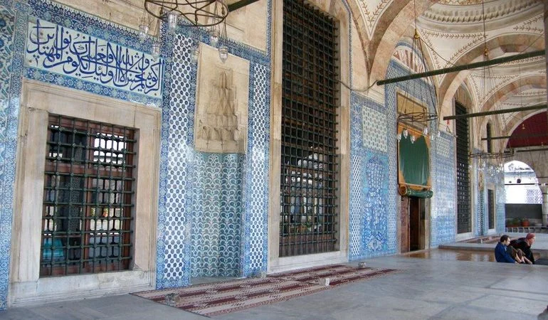 Rüstem Pasha Mosque portico — tiled walls, calligraphic panels and grilled windows under the arcade