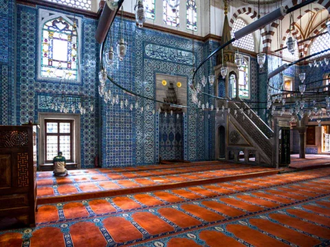 Rüstem Pasha Mosque prayer hall — red carpet, blue tiled walls, mihrab and minbar