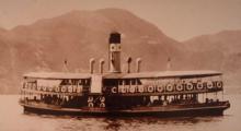 A sepia archival photograph of an early Star Ferry vessel crossing Victoria Harbour in the early twentieth century, with the hills of Hong Kong behind