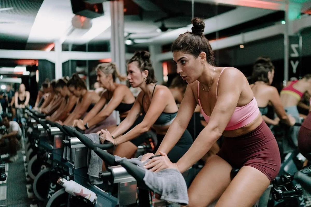 Zycle Canggu — indoor cycling studio on Jl. Nelayan, riders in formation on Stages bikes under green ambient lighting