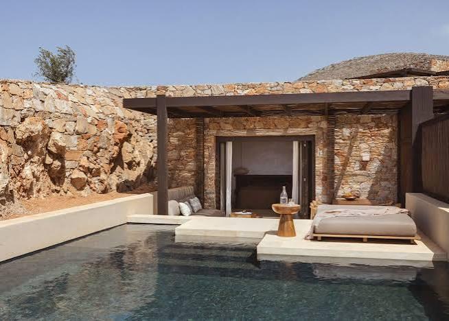 Gundari suite exterior — dry-stone walls, timber pergola and a private infinity pool set into the cliff, with day beds beside the water