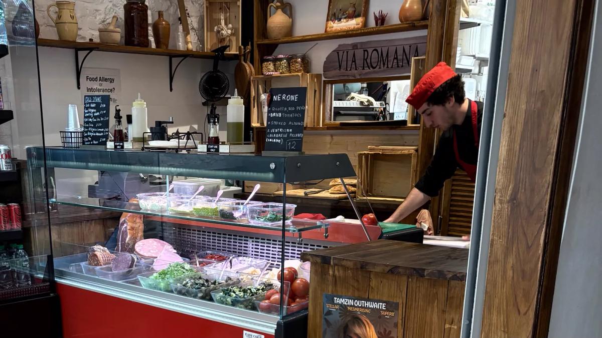 Inside Via Romana Deli — the counter where owners Nico and Theresa build sandwiches to order on warm Roman flatbread